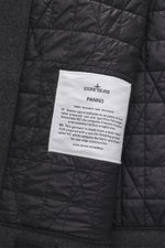 Close-up inside view of Stone Island Jacke 'No Seasons Garment Dyed Crinkle Reps NY' graugrün showing quilted black lining and white fabric label stitched on dark grey wool-nylon fabric.