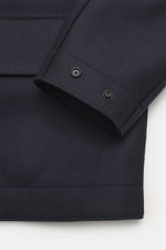 Close-up image from above of the sleeve cuff and patch pocket of the Stone Island Jacket 'Panno Ghost Piece' navy, showing mix of wool and microfiber, textured feel, slim fit, five-button placket, patch chest pockets, front pockets with flap, turn-down co