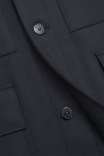 Close-up detail of Stone Island Jacket 'Panno Ghost Piece' navy front, showing slim fit, five-button placket, patch chest and flap front pockets, turn-down collar, tonal compass badge on sleeve, sleeve cuffs with snap button, textured mix of wool and micr