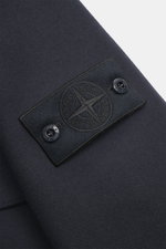 Close-up view of the sleeve of the Stone Island Jacket 'Panno Ghost Piece' navy, showing the tonal compass badge with two snap buttons on textured wool and microfiber fabric.