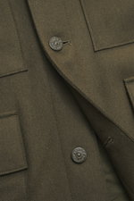 Close-up front view of Stone Island Jacket 'Panno Ghost Piece' olive showing mix of wool and microfiber, textured feel, slim fit, five-button placket, patch chest pockets, front flap pockets, turn-down collar, tonal compass badge on sleeve, buttoned sleev