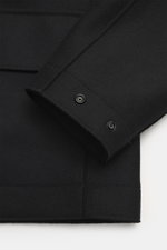 Close-up front angle of Stone Island Jacket 'Panno Ghost Piece' black, showing wool and microfiber mix, textured feel, slim fit, five-button placket, patch chest pockets, front flap pockets, turn-down collar, tonal compass badge on sleeve, snap button cuf