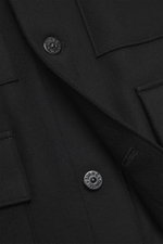 Close-up front detail of Stone Island Jacket 'Panno Ghost Piece' black showing slim fit, five-button placket, patch chest pockets, front flap pockets, turn-down collar, tonal compass badge on sleeve, snap button cuffs, textured wool and microfiber mix, sm