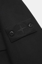 Close-up front sleeve view of Stone Island Jacket 'Panno Ghost Piece' black, mix of wool and microfiber, textured feel, slim fit, five-button placket, patch chest pockets, front pockets with flap, turn-down collar, tonal compass badge on the sleeve, sleev