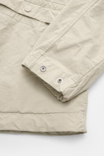 Stone Island Jacket 'David Light-TC Ghost Piece' sand close-up from above showing elastic sleeve cuffs with snap button, high-quality microfiber, anti-drop finish, velvety feel, regular fit, concealed button placket, turn-down collar, slanted welt pockets