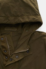 Alt-Tag (124 Zeichen):
Nahaufnahme der olivfarbenen Stone Island Jacke 'Nylon Smerigliato Ghost Piece' mit Kapuze, Reißverschluss und Knöpfen, weiches Nylon.