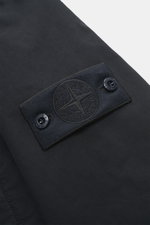 Close-up, top-down view of the tonal compass badge on the Stone Island Down Jacket 'Ghost Piece David-TC' navy, made of high-quality microfiber with a velvety touch, garment dyed, featuring warm down filling, Regular Fit, robust two-way zipper, wind flap 