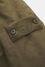 Nahaufnahme des tonalen Kompass-Badges an der Ärmelmanschette der olivfarbenen Stone Island Jacke 'David-TC Ghost Piece' aus hochwertiger Microfaser.