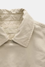 Nahaufnahme der Stone Island Jacke 'David-TC Ghost Piece' sand mit hochgeschlossenem variablen Umlegekragen, weichem Stoff und tonalem Badge.