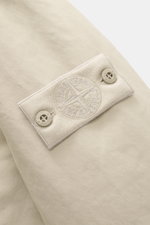 Nahaufnahme des tonalen Kompass-Badges an der Stone Island Jacke 'David-TC Ghost Piece' sand aus weicher Microfaser mit Anti-Drop-Finish.
