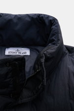Close-up view of the collar and zipper area of the Stone Island Down jacket 'Garment Dyed Crinkle Reps NY' dark navy, showcasing its innovative coated crinkle microfiber, garment-dyed fabric, and high-quality down lining for wind and water repellency.