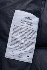 Close-up of the interior label of the Stone Island Down jacket 'Garment Dyed Crinkle Reps NY' dark navy, showing fabric details and care icons.