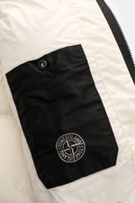 Close-up inside view of Stone Island Down jacket 'Garment Dyed Crinkle Reps NY' cream showing black interior pocket with logo button and zipper detailing, highlighting innovative coated material and garment-dyed crinkle look.