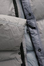 Close-up view of the Stone Island Down jacket 'Garment Dyed Crinkle Reps NY' grey, showing the crinkle microfiber fabric, YKK zipper, snap button, and lightweight, garment-dyed material with a warm down lining. Innovative coated material combines outdoor 