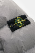 Close-up rear view of Stone Island Down jacket 'Garment Dyed Crinkle Reps NY' grey showing the signature black compass badge on innovative coated crinkle microfibre.
