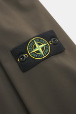 Nahaufnahme des Stone Island Softshell-Blouson 'Light Soft Shell-R e.dye Technology' graubraun mit Kompass-Badge, glattem Griff und elastischer Microfaser.