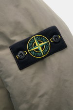 Nahaufnahme der Stone Island Jacke 'Micro Reps' graugrün aus Baumwoll-Canvas mit weichem Griff und typischem Kompass-Badge, frontal fotografiert.