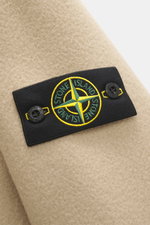 Stone Island Jacke 'Heavy Melton' beige, Detailansicht des Kompass-Badges auf schwerem Woll-Kaschmir-Gewebe, robuste Qualität, Nahaufnahme.