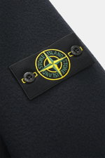 Close-up of the Stone Island Pea Coat Navy showing the felted virgin wool and cashmere blend fabric and logo badge from a side angle.

<p>This pea coat by STONE ISLAND features a felted surface made of fine virgin wool with a cashmere blend, making it a s