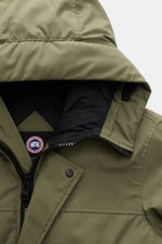 Canada Goose Down parka 'Langford' grey green shown from a top front close-up perspective, highlighting the hood, two-way zip, storm flap with snap buttons, and Arctic-Tech material; urban style with an arctic background – the down parka 'Langford' by CAN