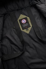 Canada Goose Down parka 'Langford' grey green shown from an interior close-up perspective, highlighting the black Arctic-Tech lining, internal rucksack straps with embossed branding, and the distinctive label patch on a green fabric backing. Urban style w