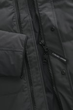 Nahaufnahme der Canada Goose Daunenjacke 'Wyndham' dunkelgrau von vorne, Slim Fit, wasserabweisend mit glattem Griff, Windblende, Daunenfüllung, Kapuze, Taschen, Weblabel und Innenfutter.