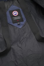 Close-up interior view of the Canada Goose Down jacket 'Wyndham' grey blue showing the label and black straps, made of high-quality microfiber and cotton, smooth feel, warm down filling, slim fit, high-closing two-way zipper, wind flap with snap buttons, 