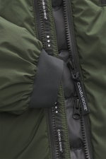 Nahaufnahme der Canada Goose Daunenjacke 'Lodge Hoody' dunkelgrün, Detail von Reißverschluss, elastischem Ärmelbündchen und Ripstop-Gewebe.