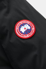 Close-up side view of the Canada Goose Down jacket 'Lodge Hoody' black showing the red and white Arctic Program patch on ripstop microfiber fabric. Maximum comfort in a lightweight design: Padded hood and lightweight down lining make the self-stowing down