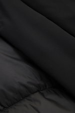 Close-up shot of the black Woolrich Down jacket 'Matt' black fabric, showing high-quality microfiber and quilted lining fabric, highlighting wind- and water-repellent, warm down filling, slim fit, durable two-way zipper, wind flap with snap buttons, high-