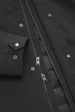 Close-up front view of Woolrich Softshell down jacket 'Barrow' black showing two-way zipper, snap buttons, adjustable cuff, and quilted lining fabric, made of softshell elastic microfiber with lightweight duck down and graphene filling, water-repellent, s