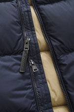 Close-up front view of Woolrich Down jacket dark blue showing durable two-way zipper, high-quality microfiber with smooth feel, warm down filling, quilted lining fabric, piped front pockets, adjustable hem, slim fit, and two inner pockets.
