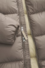 Nahaufnahme der Woolrich Daunenjacke taupe von oben, hochwertige Microfaser, geschmeidiger Griff, wärmende Daunenfüllung, Slim Fit, robuster Zwei-Wege-Reißverschluss, paspelierte Fronttaschen, regulierbarer Saum, gesteppter Futterstoff, zwei Innentaschen.