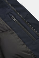 Close-up view of the Woolrich Down jacket 'Heavy GTX' navy showing high-quality microfiber, robust two-way zipper, wind flap with buttons, and quilted lining fabric. The jacket features wind- and water-repellent material, warm down filling, slim fit, high