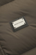 Close-up front perspective of the Emporio Armani Down jacket brown showing a metal logo patch on high-quality microfiber fabric with soft touch. Features warm down filling, slim fit, two-way zipper, wind flap with snap buttons, detachable hood, front pock
