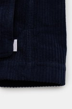 Close-up of the hem and label detail of the 04651/ A trip in a bag Corduroy pea coat navy, showing the soft, voluminous wide wale cotton corduroy fabric and ribbed cuff from a front-side perspective.