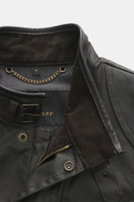 Close-up front view of Belstaff Waxed jacket 'Trialmaster Phoenix' dark brown collar showing waxed cotton, corduroy inner side, leather piping, buckle strap, zipper, and snap buttons, part of the limited Phoenix Collection known for durability and timeles