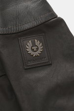 Nahaufnahme der Belstaff Wachsjacke 'Trialmaster Phoenix' dunkelbraun, Detail des Logos auf gewachster Baumwolle mit Lederbesatz.