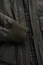 Close-up front view of Belstaff Wax blouson 'Mount Jacket' dark olive showing ribbed cuff, metal zipper, patch pocket, and checked cotton lining.