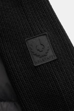 Close-up front view of Belstaff Down knit jacket 'Compound' black showing soft pure wool patent knit, quilted microfiber, and logo patch.