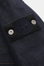 Close-up side view of the Stone Island Denim jacket 'Indigo Denim-Raw' navy showing the raw denim fabric, typical texture, and black compass badge with silver buttons on the upper sleeve.