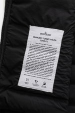 Close-up inside view of the Stone Island Down Jacket 'Seamless Tunnel Nylon Down-TC' black showing white fabric label with detailed product info.

<p>The STONE ISLAND 'Seamless Tunnel Nylon Down-TC' jacket impresses with innovative manufacturing, lightwei