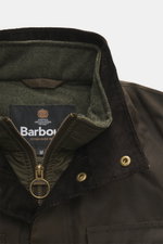 Barbour Wachsjacke 'Ogston' khaki aus wasserabweisender, gewachster Baumwolle, Nahaufnahme des Stehkragens mit Reißverschluss, Druckknöpfen und Tartan-Futter.