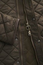 Barbour Quilted jacket 'Powell Quilt' dark olive close-up from above showing quilted microfiber, two-way zipper with ring pull, fleece lining, and faux leather trim.