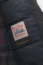 Nahaufnahme der Innenseite des Barbour Wachsparka 'Northfield Waterproof' navy mit gestepptem Futter, Tartan-Details und Markenlabel.