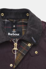 Close-up front view of Barbour Wax jacket 'Beaufort Icons' purple showing corduroy collar, gold zipper, snap buttons, and tartan lining.