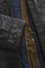 Close-up front view of Barbour Wax parka 'Ursula' dark navy showing waxed cotton with typical material texture, water-repellent, breathable fabric, double front with robust two-way zipper, smooth button placket, chest pocket with flap and button, front po