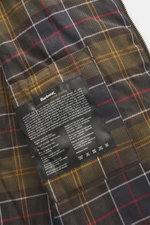 Close-up inside view of Barbour Wax parka 'Bedale' dark olive showing the signature tartan lining and classic wax care guide label.

Description: An icon among wax jackets, the BARBOUR 'Bedale' returns this season as a parka, with extra length and even mo