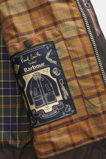 Nahaufnahme des charakteristischen Tartan-Innenfutters der Barbour Wachsjacke 'Gamefair' dunkelgrün mit Paul Smith Label und Reißverschluss

Beschreibung: Das Bild zeigt aus nächster Nähe das innenliegende, farbige Tartan-Futter der Barbour Wachsjacke '