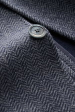 Nahaufnahme der Fedeli Cashmere Jersey-Jacke 'Damon' grau gemustert mit Fischgrat-Muster und Knopf, Detailansicht von oben.